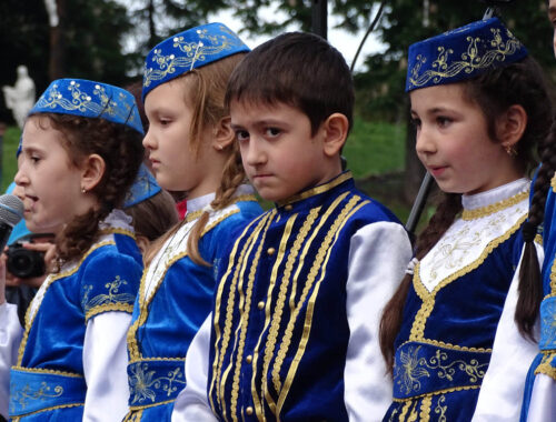 Enfants tatars vêtus de tenues traditionnelles bleues lors d'une cérémonie en Ukraine