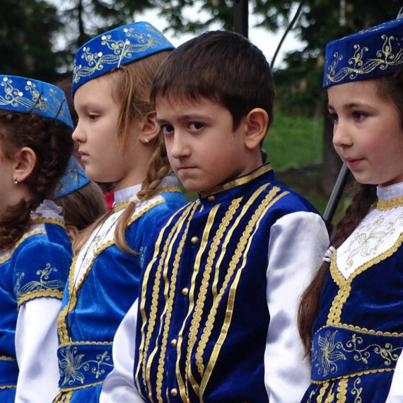 Enfants tatars vêtus de tenues traditionnelles bleues lors d'une cérémonie en Ukraine