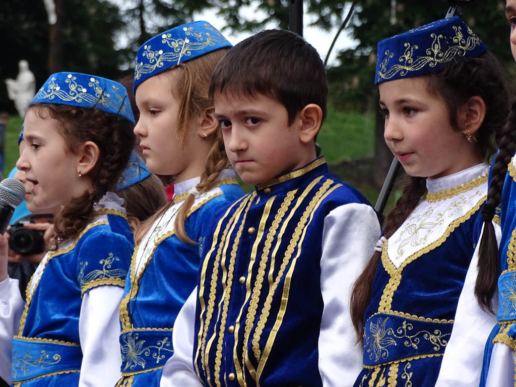 Enfants tatars vêtus de tenues traditionnelles bleues lors d'une cérémonie en Ukraine