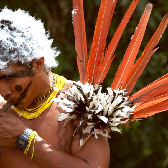 Homme Yanomami peint sur le visage et le corps en rouge urucum et noir genipapo. Il est aussi décoré avec des plumes d'oiseaux