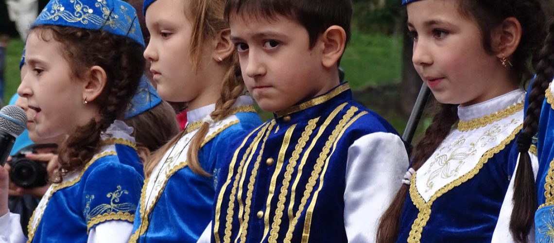 Enfants tatars vêtus de tenues traditionnelles bleues lors d'une cérémonie en Ukraine